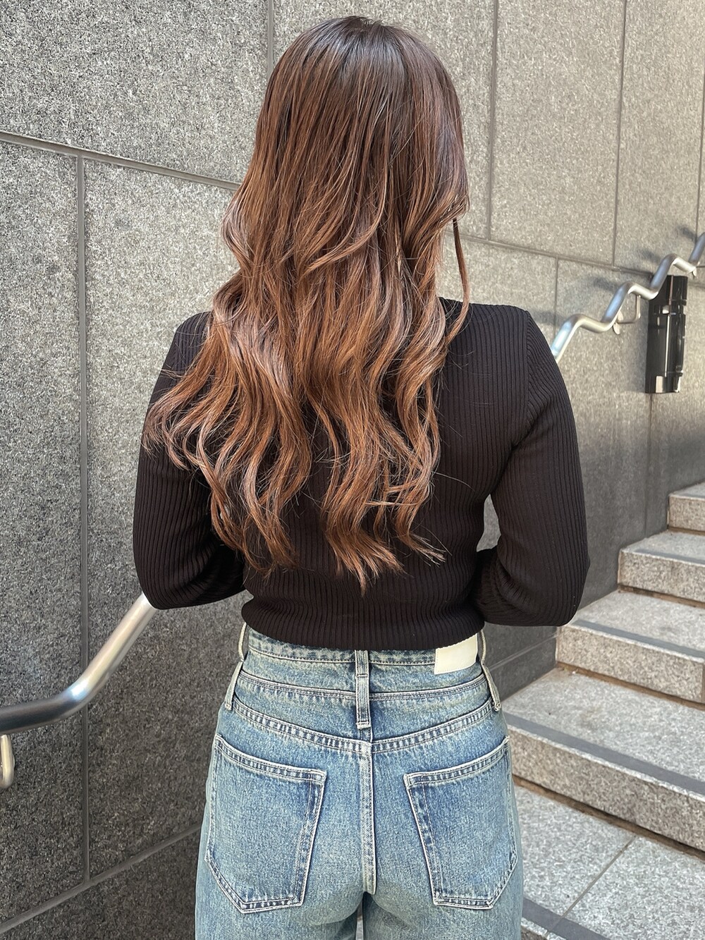 ブラック系のニット/セーター、ブルー系のデニムパンツ、ブラック系のスリッポンを着用したレディースの秋コーディネートの6枚目の写真