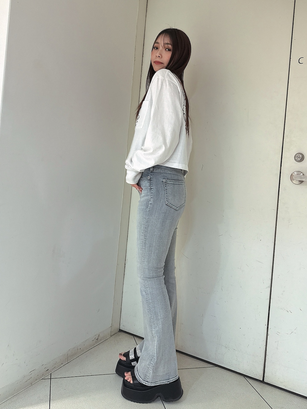 ブルー系のデニムパンツ、ホワイト系のTシャツ/カットソー、ブラック系のサンダルを着用したレディースの春コーディネートの2枚目の写真