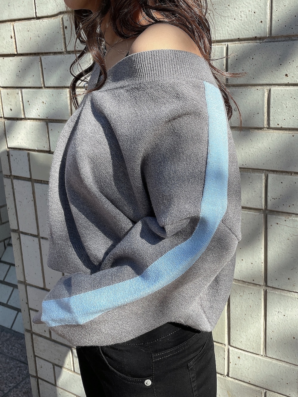 グレー系のニット/セーター、ブラック系のキャミソール、ブラック系のデニムパンツを着用したレディースの冬コーディネートの7枚目の写真