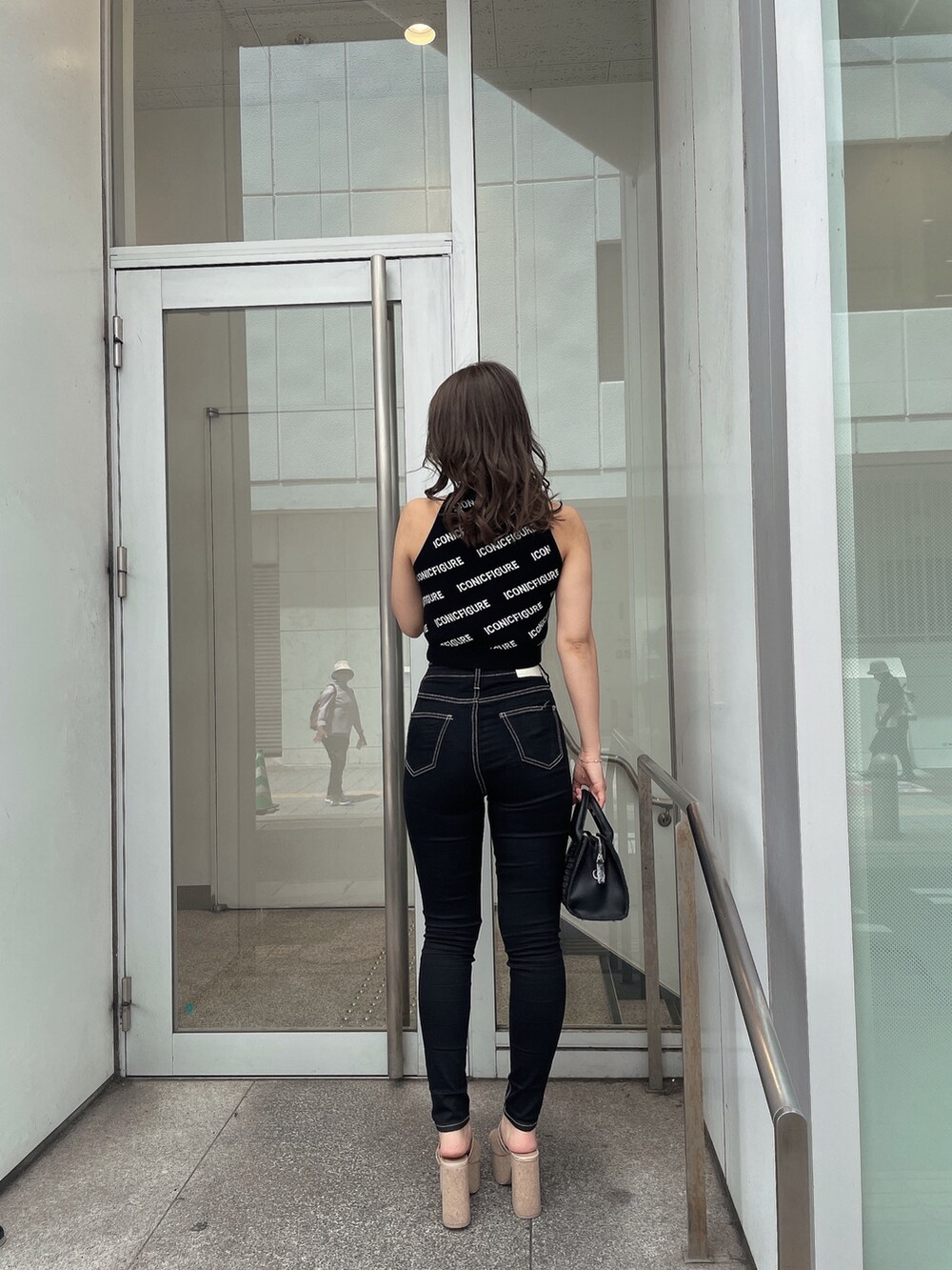 ホワイト系のサンダル、ブラック系のデニムパンツ、ブラック系のハンドバッグを着用したレディースの春コーディネートの6枚目の写真