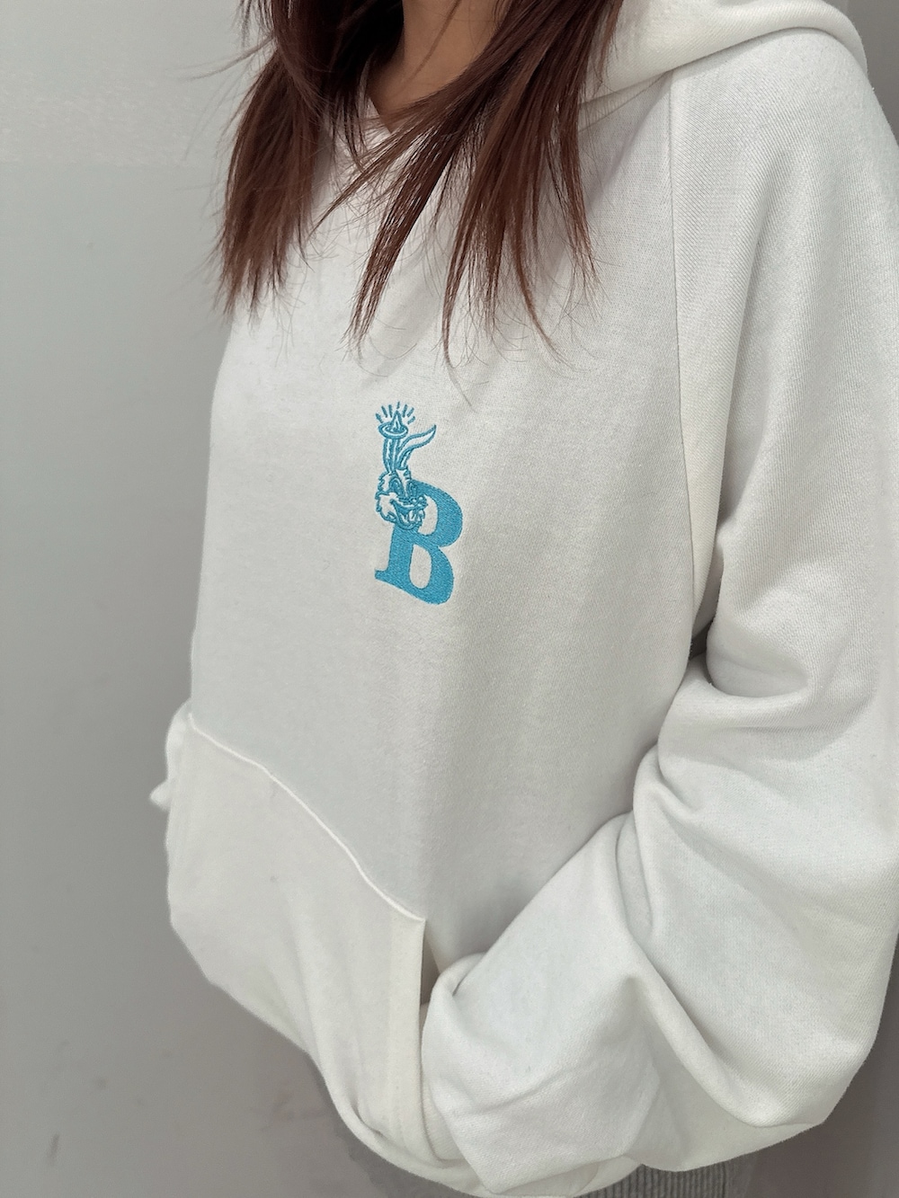 グレー系のワンピース、ホワイト系のパーカー、ブラック系のブーツを着用したレディースの冬コーディネートの7枚目の写真