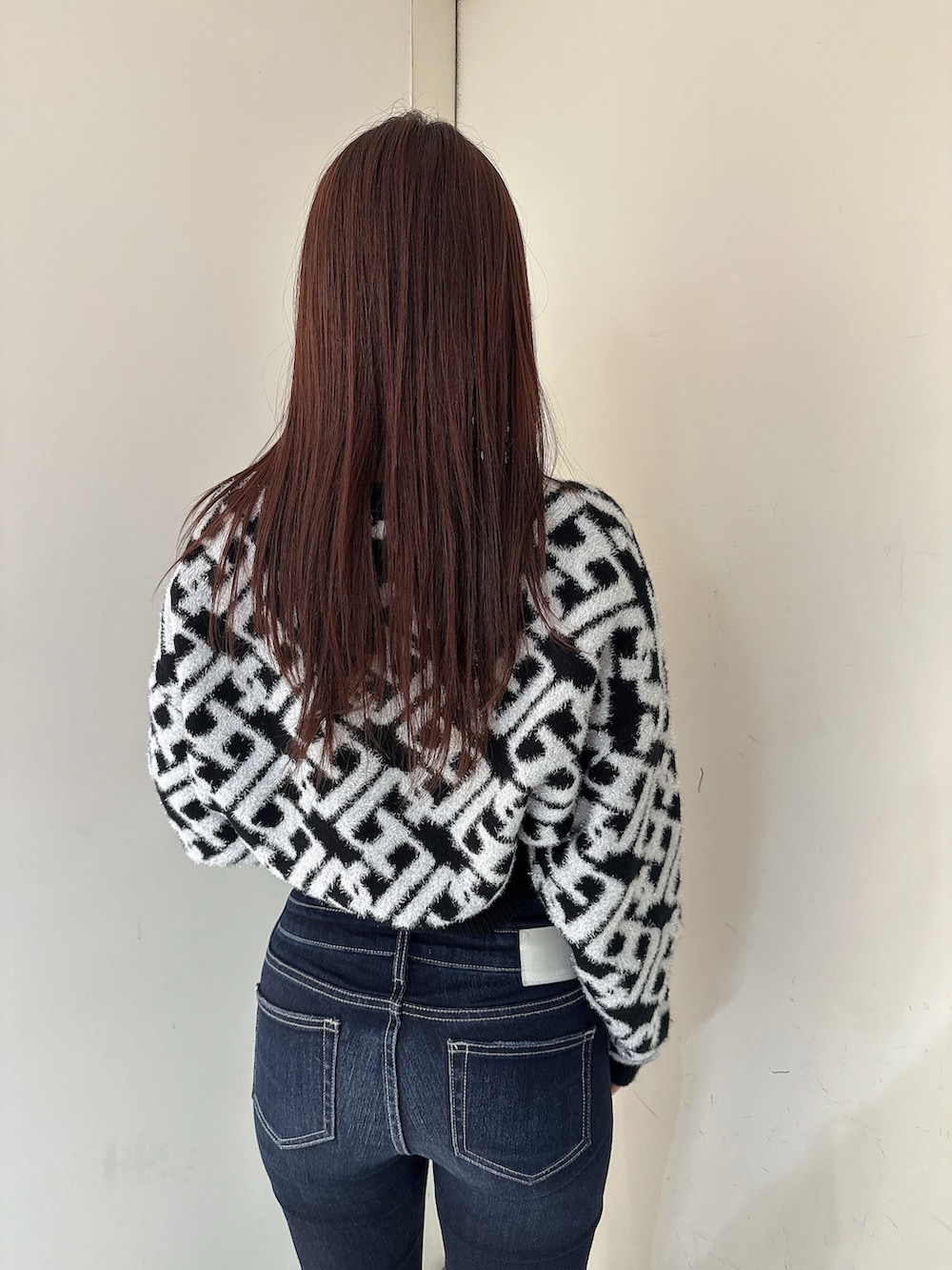 ブルー系のデニムパンツ、ブラック系のブーツ、ブラック系のニット/セーターを着用したレディースの秋コーディネートの6枚目の写真