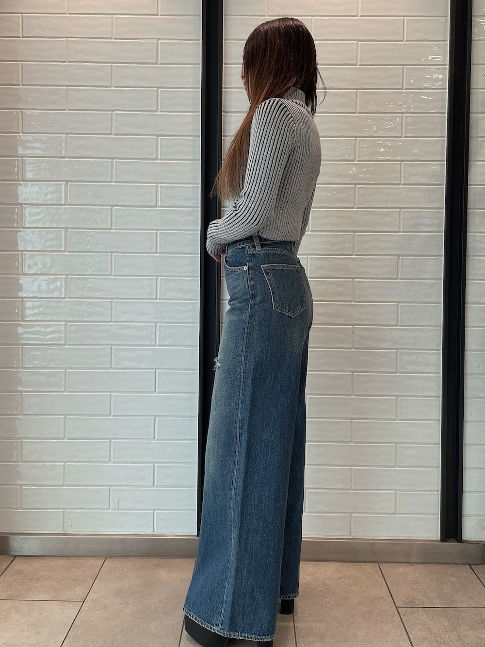 ブラック系のデニムパンツ、ブラック系のブーツ、その他のニット/セーターを着用したレディースの秋コーディネートの2枚目の写真