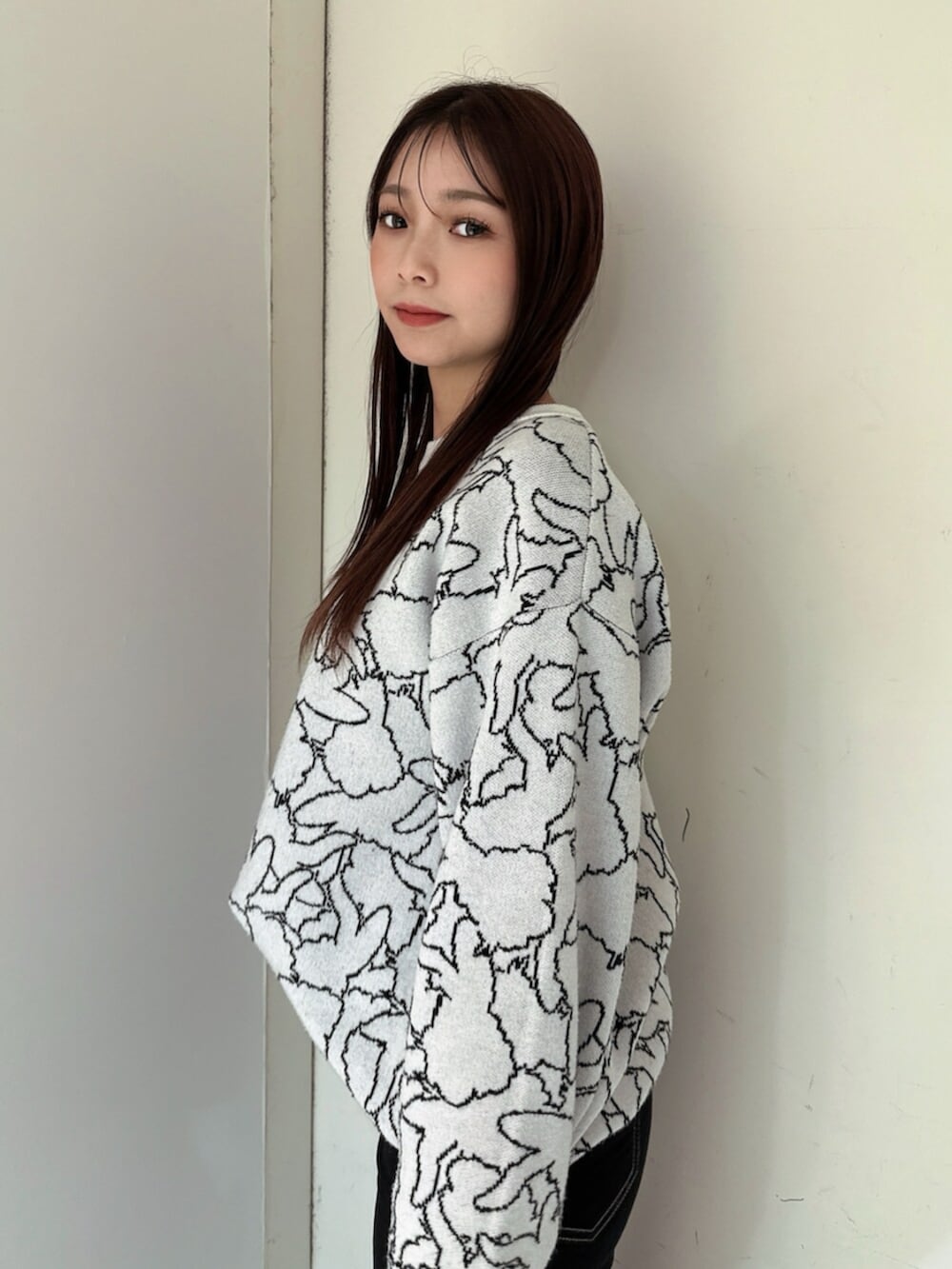 ブラック系のデニムパンツ、ブラック系のブーツ、ホワイト系のニット/セーターを着用したレディースの冬コーディネートの5枚目の写真