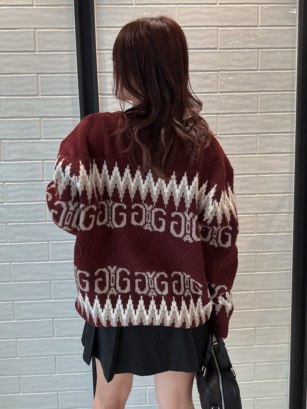 レッド系のニット/セーター、ブラック系のスカート、ブラック系のハンドバッグを着用したレディースの冬コーディネートの6枚目の写真