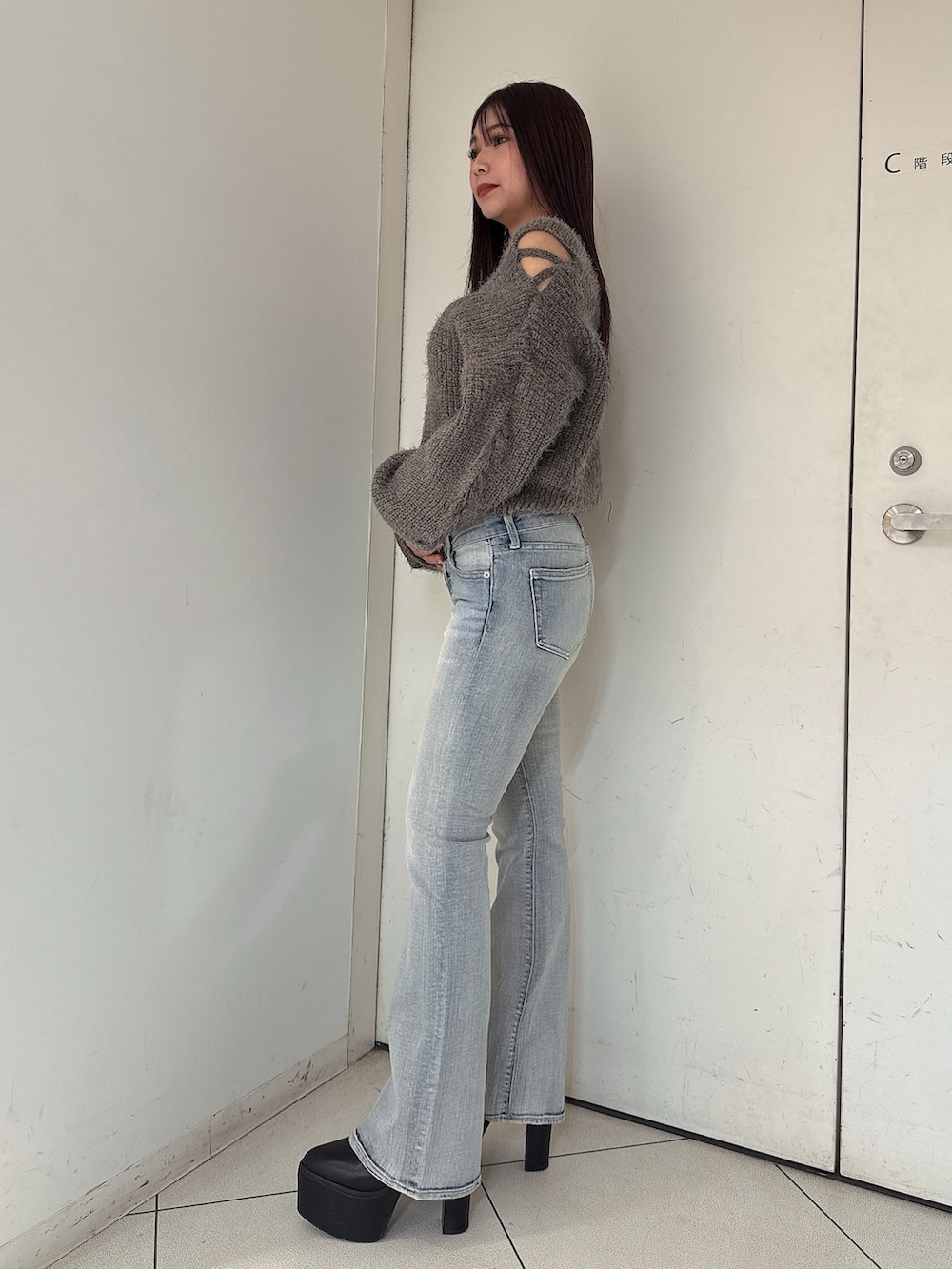 グレー系のニット/セーター、ブルー系のデニムパンツ、ブラック系のブーツを着用したレディースの秋コーディネートの2枚目の写真