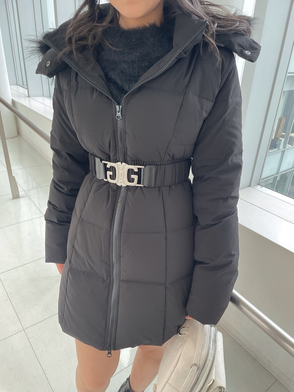 ブラック系のダウンジャケット/コート、ブラック系のワンピース、ホワイト系のバックパック/リュックを着用したレディースの冬コーディネートの6枚目の写真