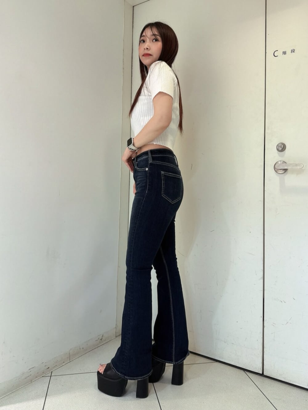 ブルー系のデニムパンツ、ブラック系のサンダル、ホワイト系のニット/セーターを着用したレディースの春コーディネートの2枚目の写真