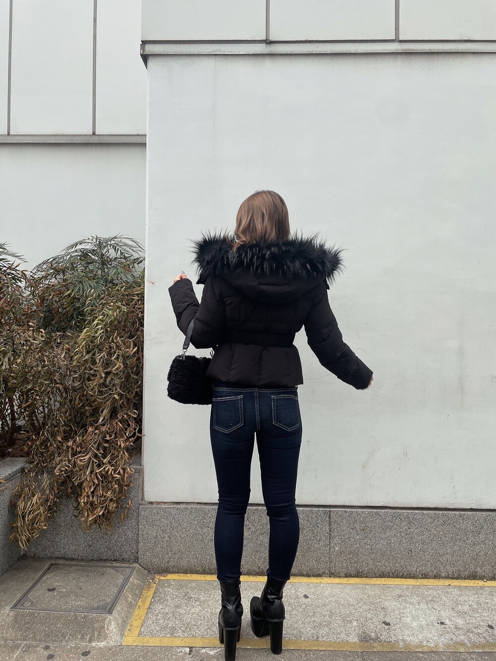 ブラック系のダウンジャケット/コート、ホワイト系のニット/セーター、ブルー系のデニムパンツを着用したレディースの秋コーディネートの2枚目の写真