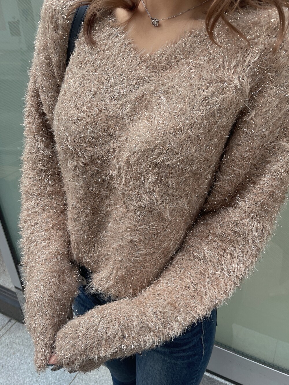 ブラック系のダウンジャケット/コート、ベージュ系のニット/セーター、ブルー系のデニムパンツを着用したレディースの秋コーディネートの7枚目の写真