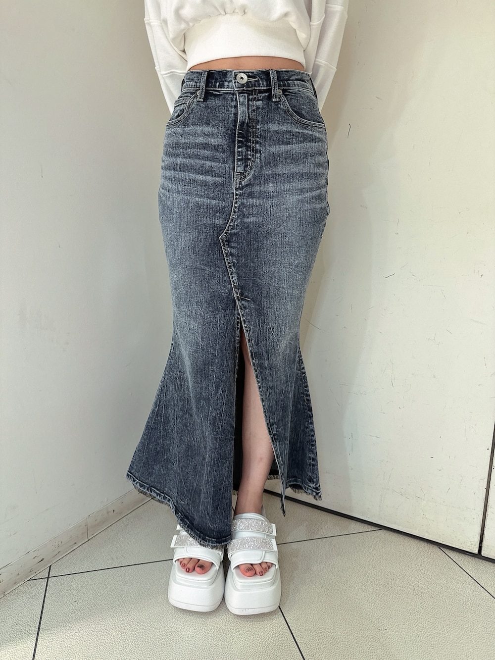 ブラック系のブーツ、ホワイト系のニット/セーター、ブルー系のデニムスカートを着用したレディースの冬コーディネートの8枚目の写真