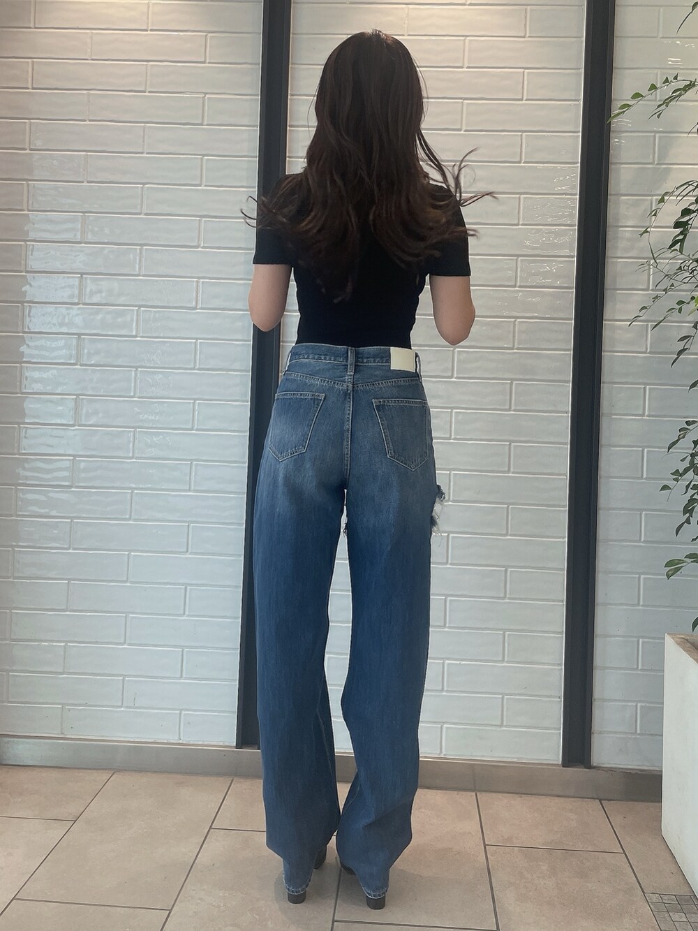 ブラック系のニット/セーター、ブラック系のサンダル、ブルー系のデニムパンツを着用したレディースの夏コーディネートの3枚目の写真