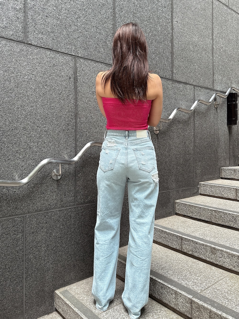 ピンク系のニット/セーター、ブルー系のデニムパンツ、ホワイト系のパンプスを着用したレディースの夏コーディネートの3枚目の写真