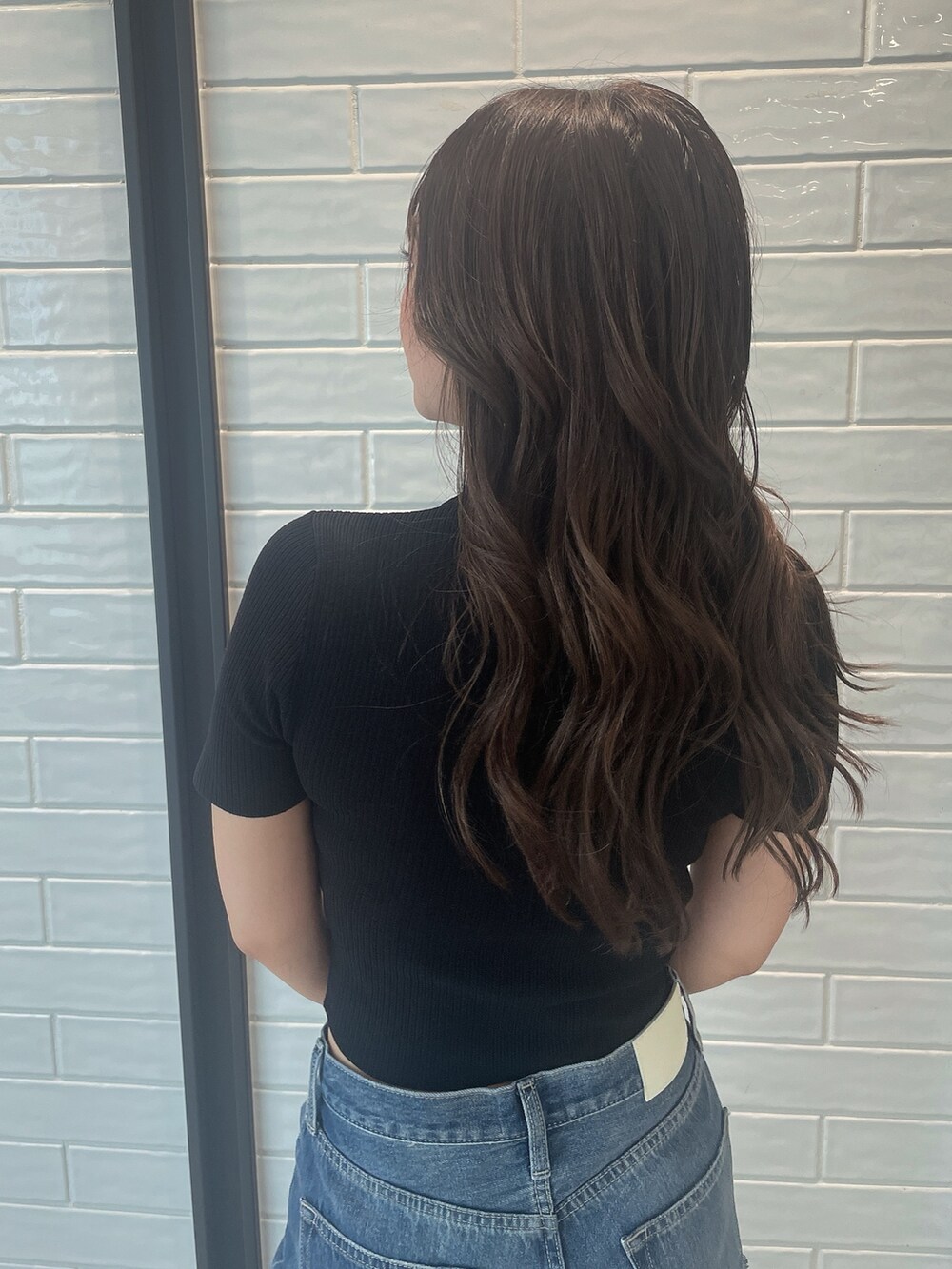 ブラック系のニット/セーター、ブラック系のサンダル、ブルー系のデニムパンツを着用したレディースの夏コーディネートの6枚目の写真