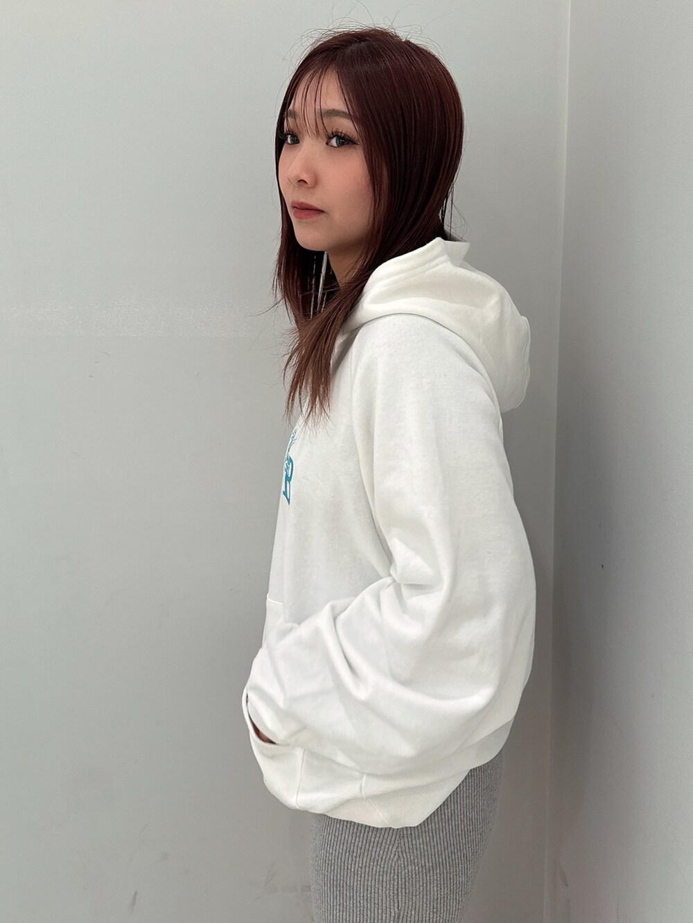 グレー系のワンピース、ホワイト系のパーカー、ブラック系のブーツを着用したレディースの冬コーディネートの5枚目の写真