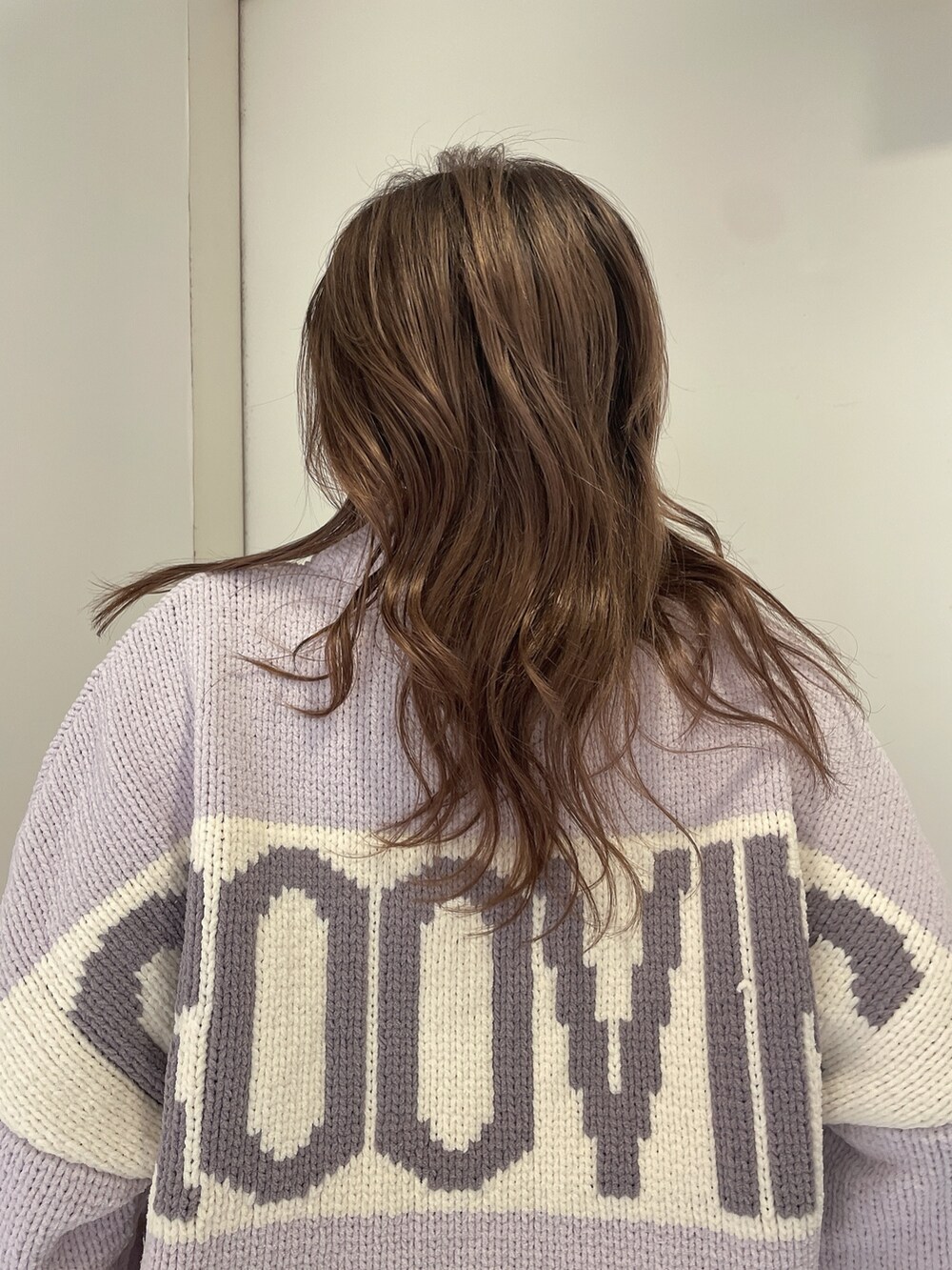 パープル系のニット/セーター、ブルー系のデニムパンツ、ホワイト系のパンプスを着用したレディースの冬コーディネートの5枚目の写真