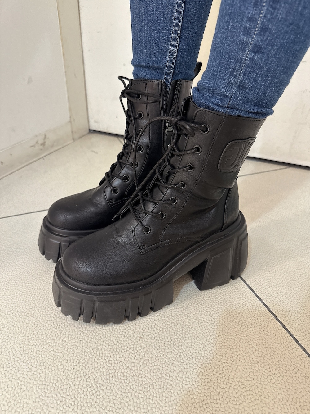 ブラック系のデニムパンツ、ブラック系のブーツ、ホワイト系のニット/セーターを着用したレディースの秋コーディネートの9枚目の写真