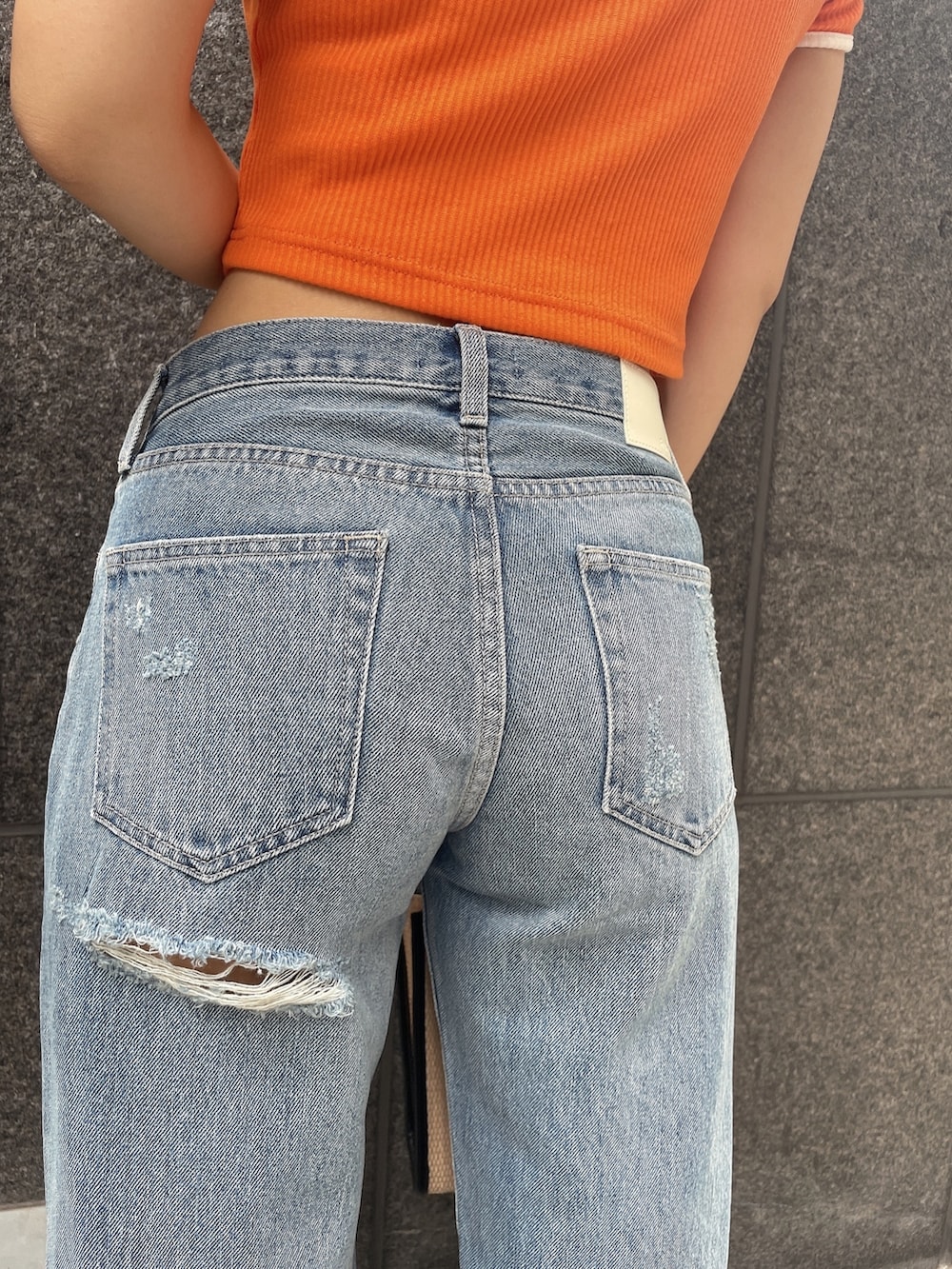 オレンジ系のTシャツ/カットソー、ブルー系のデニムパンツ、ブラック系のチューブトップを着用したレディースの夏コーディネートの8枚目の写真