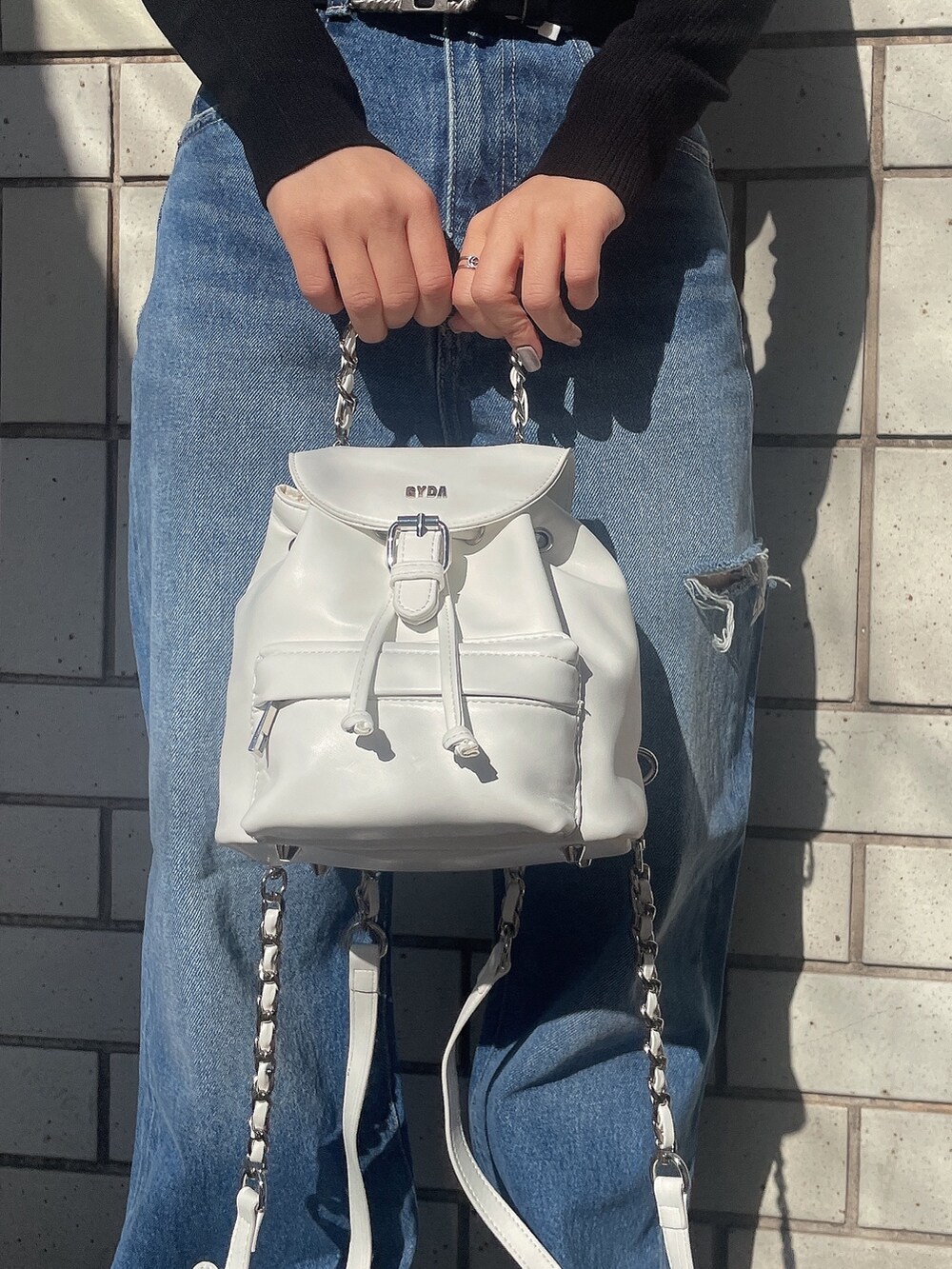 ブラック系のニット/セーター、ホワイト系のバックパック/リュック、ブルー系のデニムパンツを着用したレディースの冬コーディネートの7枚目の写真