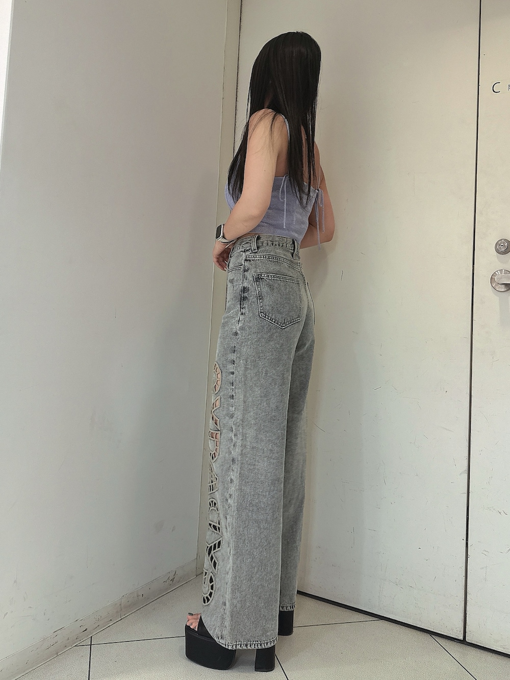 ブルー系のデニムパンツ、ブラック系のサンダル、パープル系のキャミソールを着用したレディースの春コーディネートの2枚目の写真