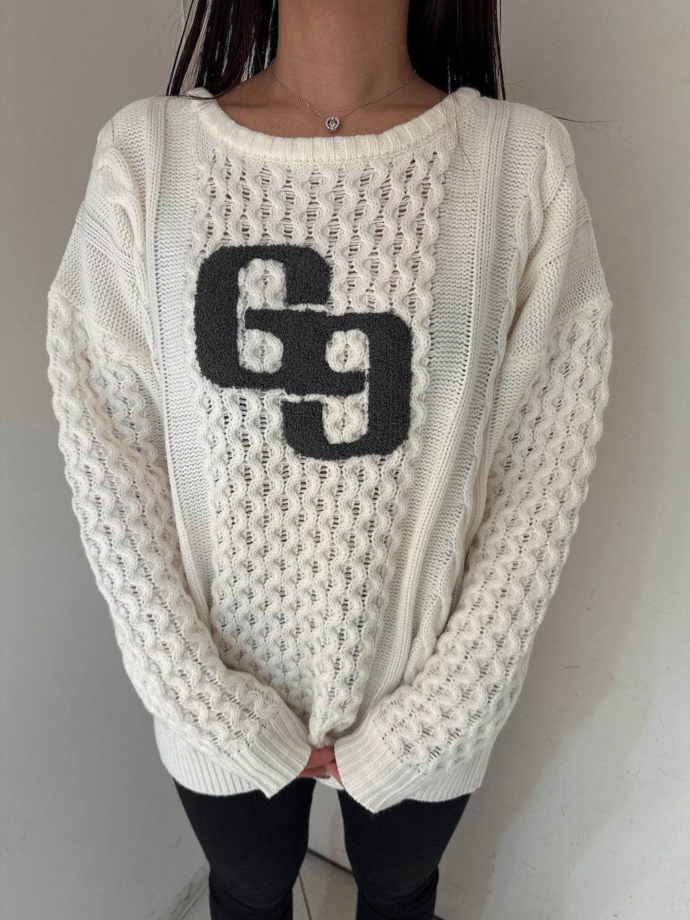 ホワイト系のニット/セーター、ブラック系のデニムパンツ、ブラック系のブーツを着用したレディースの秋コーディネートの7枚目の写真