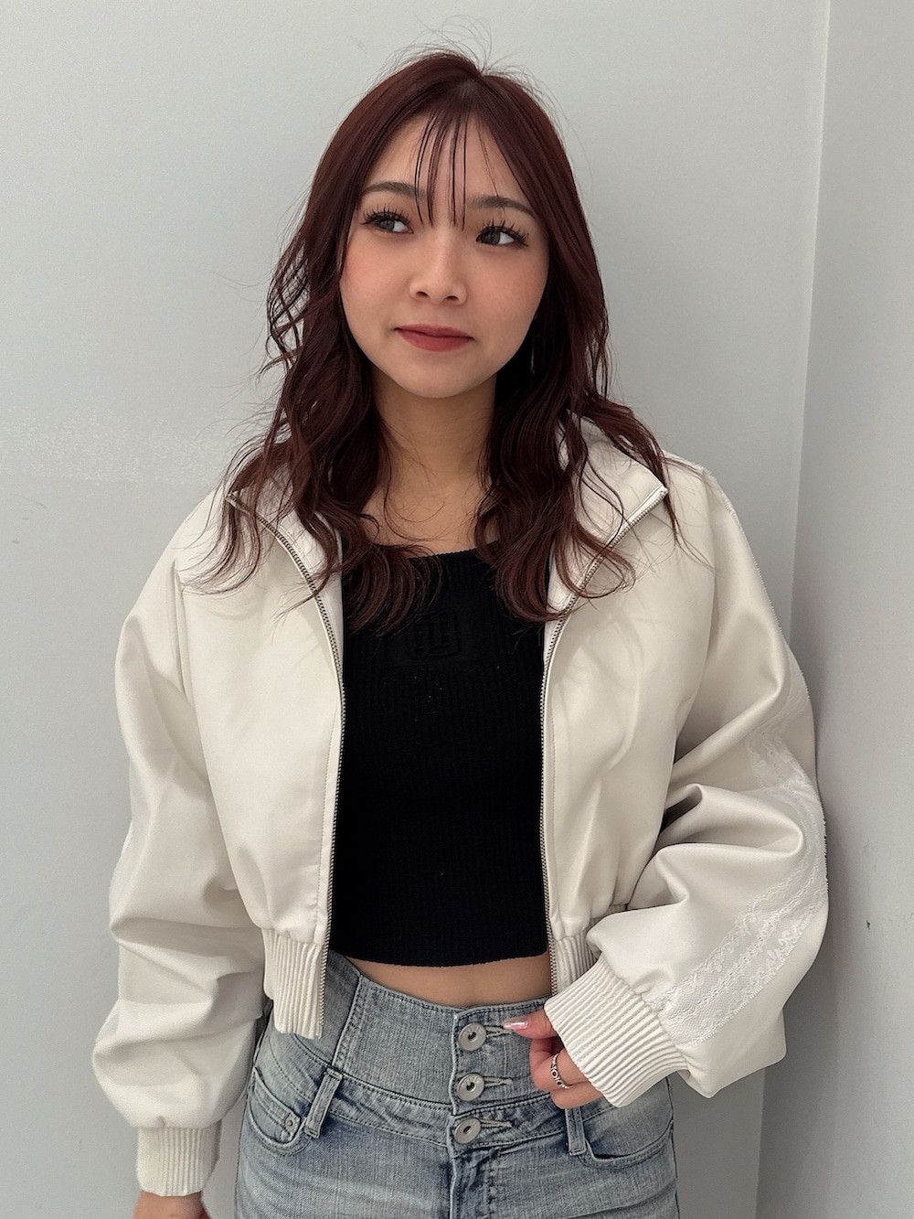 ホワイト系のブルゾン、ブラック系のニット/セーター、ブルー系のデニムパンツを着用したレディースの冬コーディネートの4枚目の写真