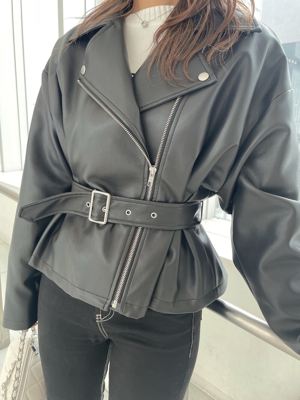 ブラック系のライダースジャケット、ブラック系のデニムパンツ、ホワイト系のハンドバッグを着用したレディースの冬コーディネートの5枚目の写真