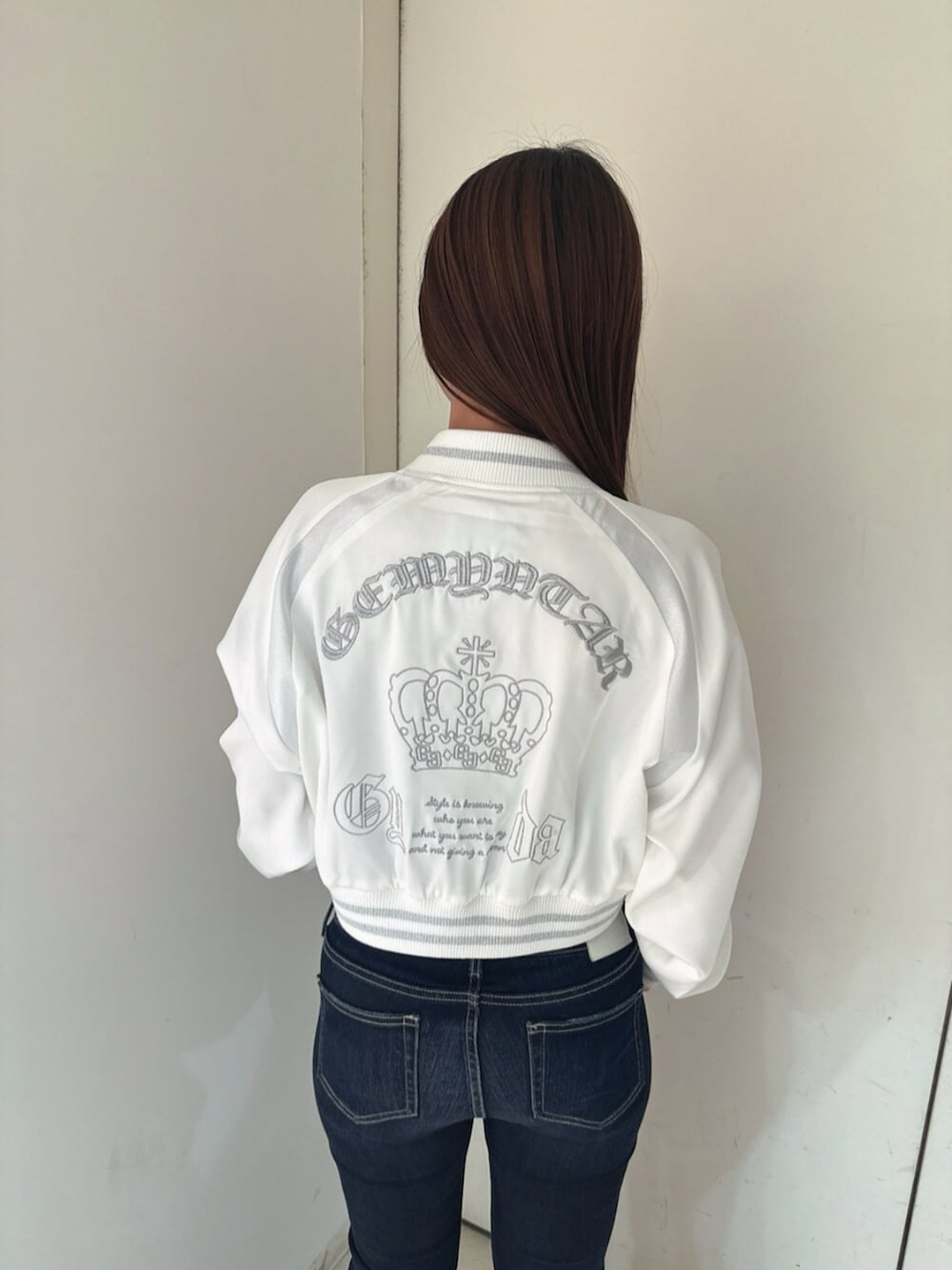 ブルー系のデニムパンツ、ブラック系のサンダル、ホワイト系のブルゾンを着用したレディースの春コーディネートの7枚目の写真