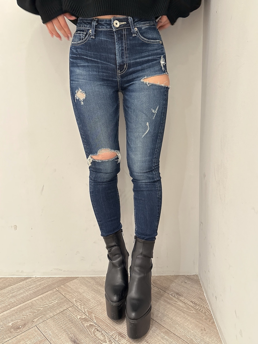 ブラック系のニット/セーター、ブルー系のデニムパンツ、ブラック系のブーツを着用したレディースの秋コーディネートの8枚目の写真