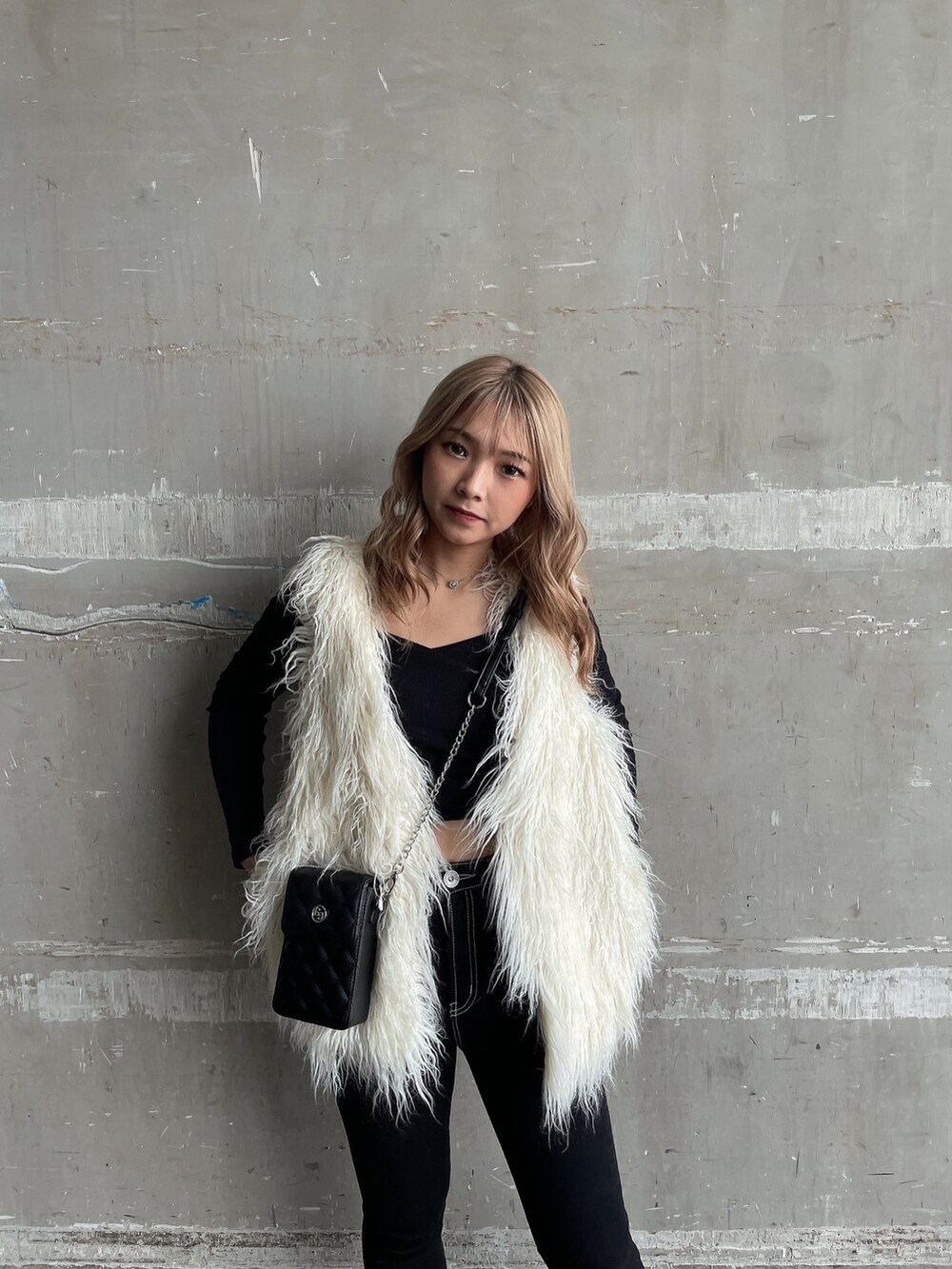 ブラック系のTシャツ/カットソー、ホワイト系のベスト、ブラック系のデニムパンツを着用したレディースの秋コーディネートの3枚目の写真