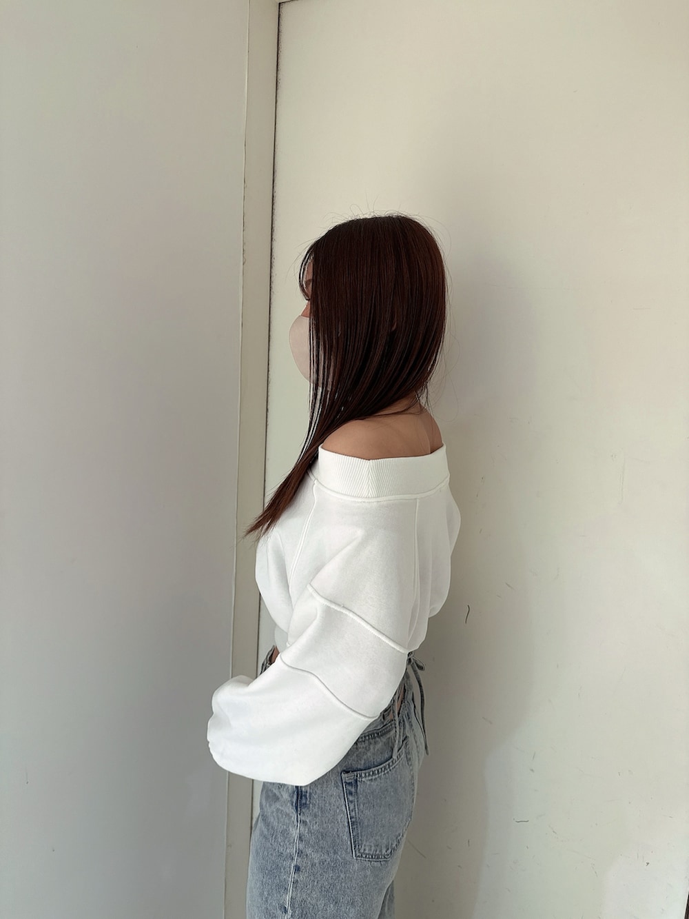 ホワイト系のスウェット、ブルー系のデニムパンツ、ホワイト系のサンダルを着用したレディースの冬コーディネートの5枚目の写真