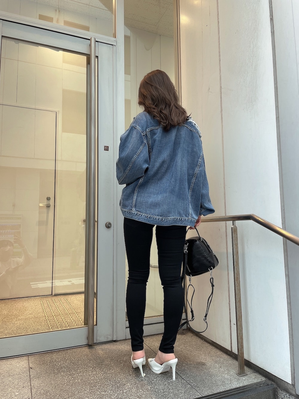 ブルー系のデニムジャケット、その他のニット/セーター、ブラック系のデニムパンツを着用したレディースの春コーディネートの2枚目の写真