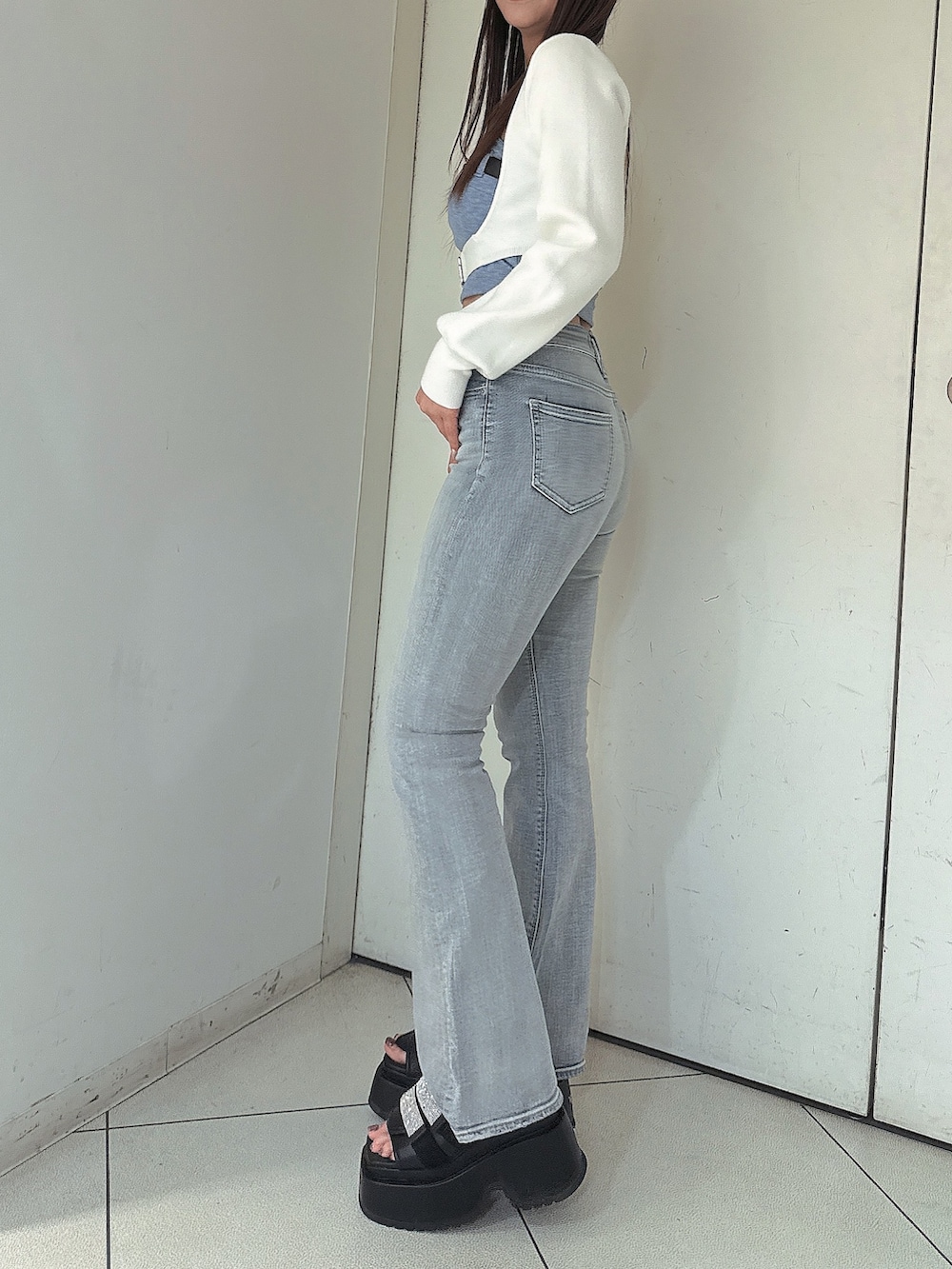 ブルー系のデニムパンツ、ブラック系のサンダル、ホワイト系のカーディガン/ボレロを着用したレディースの春コーディネートの2枚目の写真