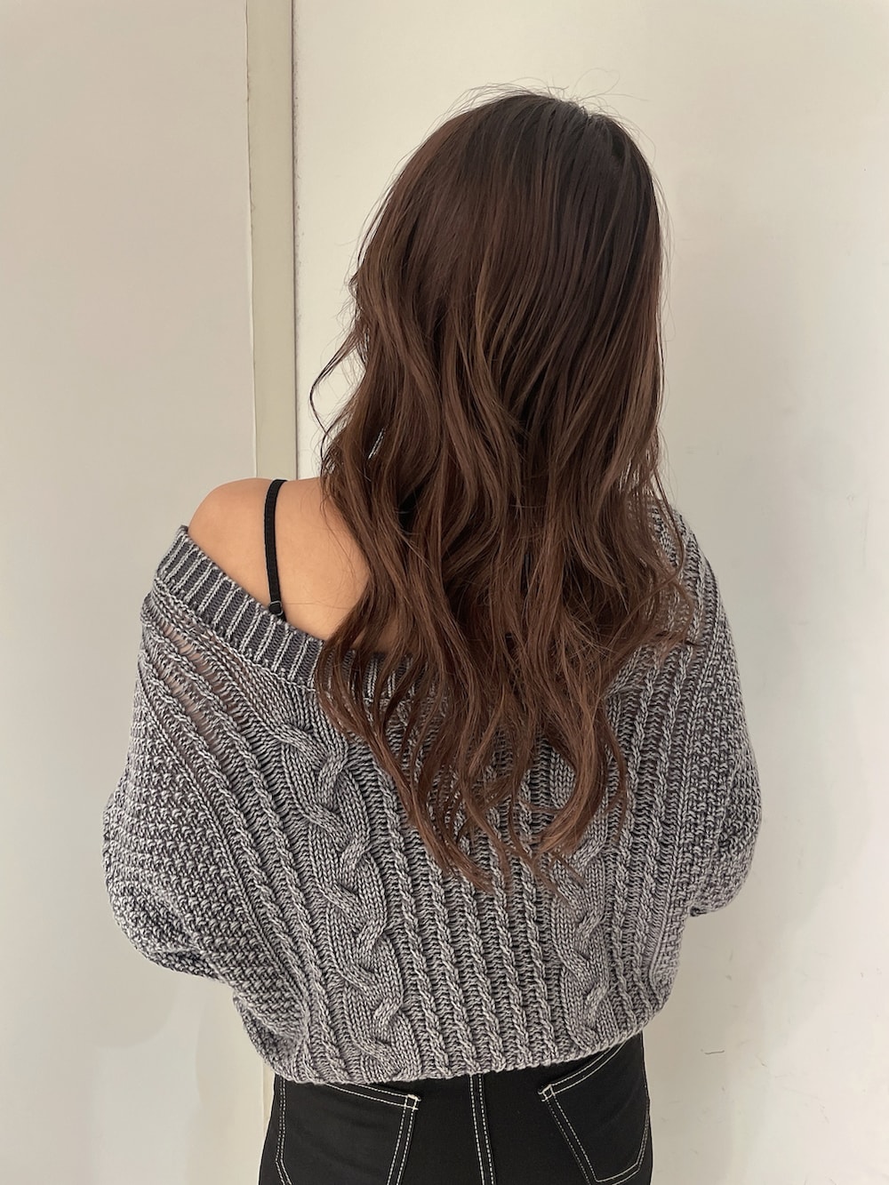 グレー系のニット/セーター、ブラック系のデニムパンツ、ホワイト系のパンプスを着用したレディースの夏コーディネートの5枚目の写真