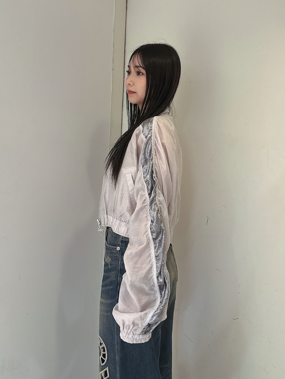 ブルー系のデニムパンツ、ホワイト系のキャミソール、ホワイト系のブルゾンを着用したレディースの春コーディネートの5枚目の写真