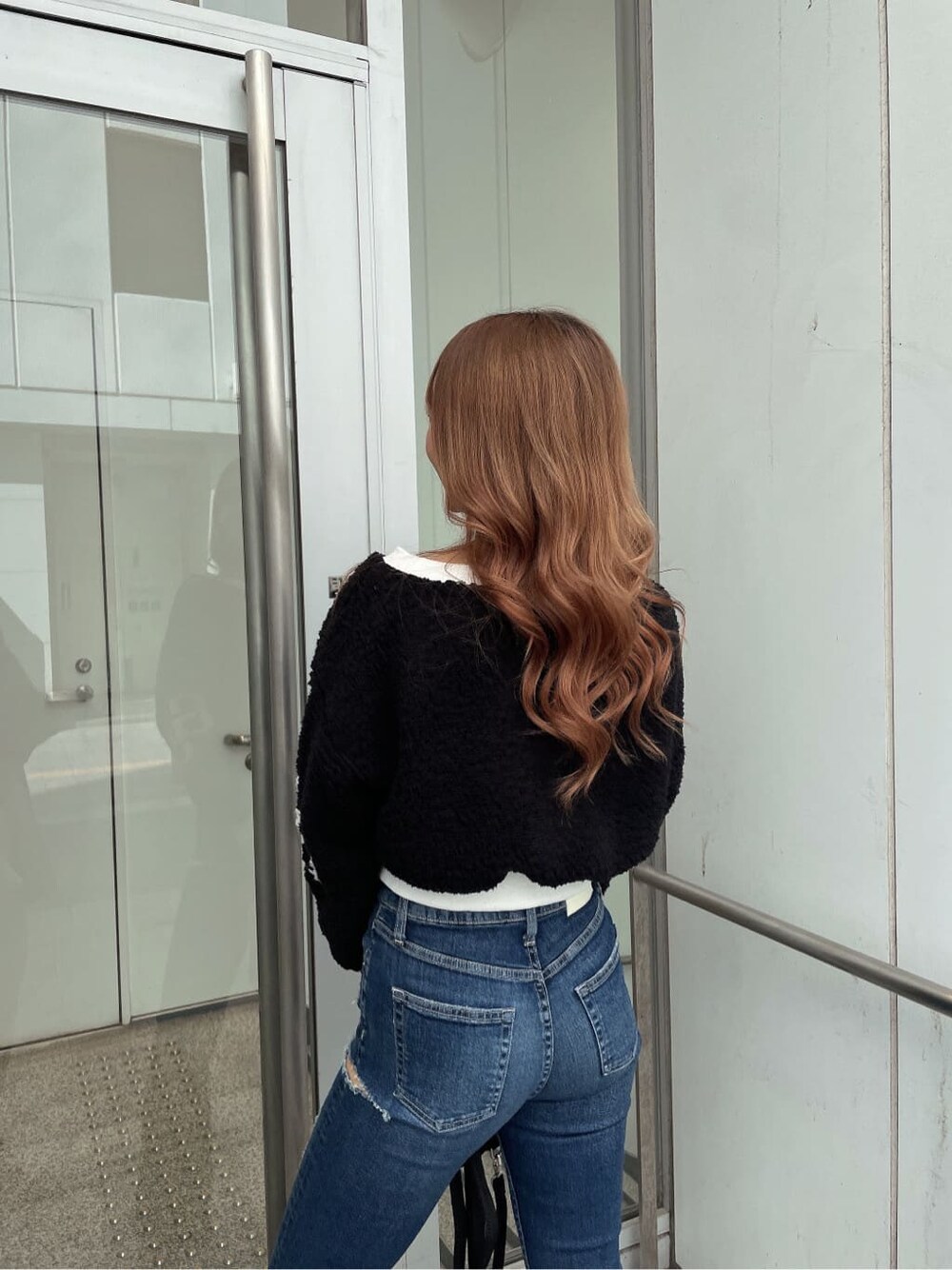 ブラック系のパンプス、ブラック系のTシャツ/カットソー、ブルー系のデニムパンツを着用したレディースの秋コーディネートの3枚目の写真