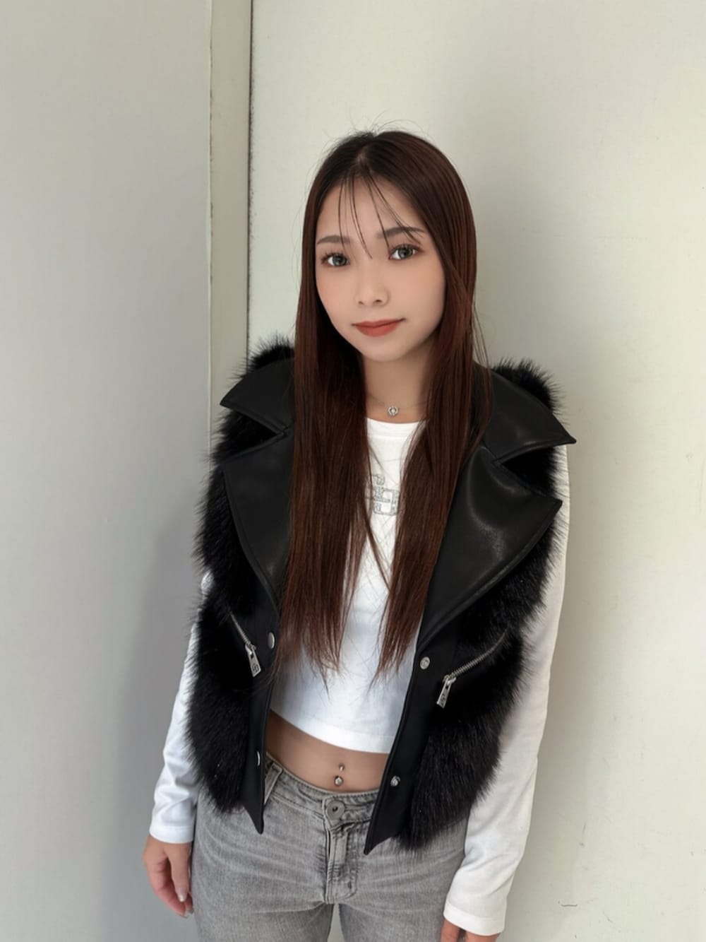 グレー系のデニムパンツ、ブラック系のブーツ、ブラック系のベストを着用したレディースの秋コーディネートの4枚目の写真
