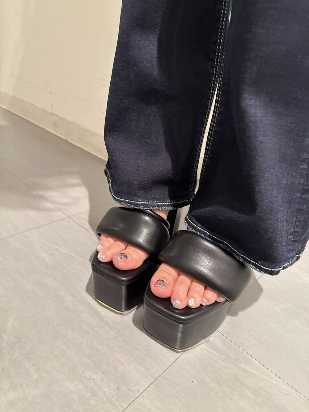 ブラック系のTシャツ/カットソー、ブルー系のデニムパンツ、ブラック系のサンダルを着用したレディースの春コーディネートの9枚目の写真