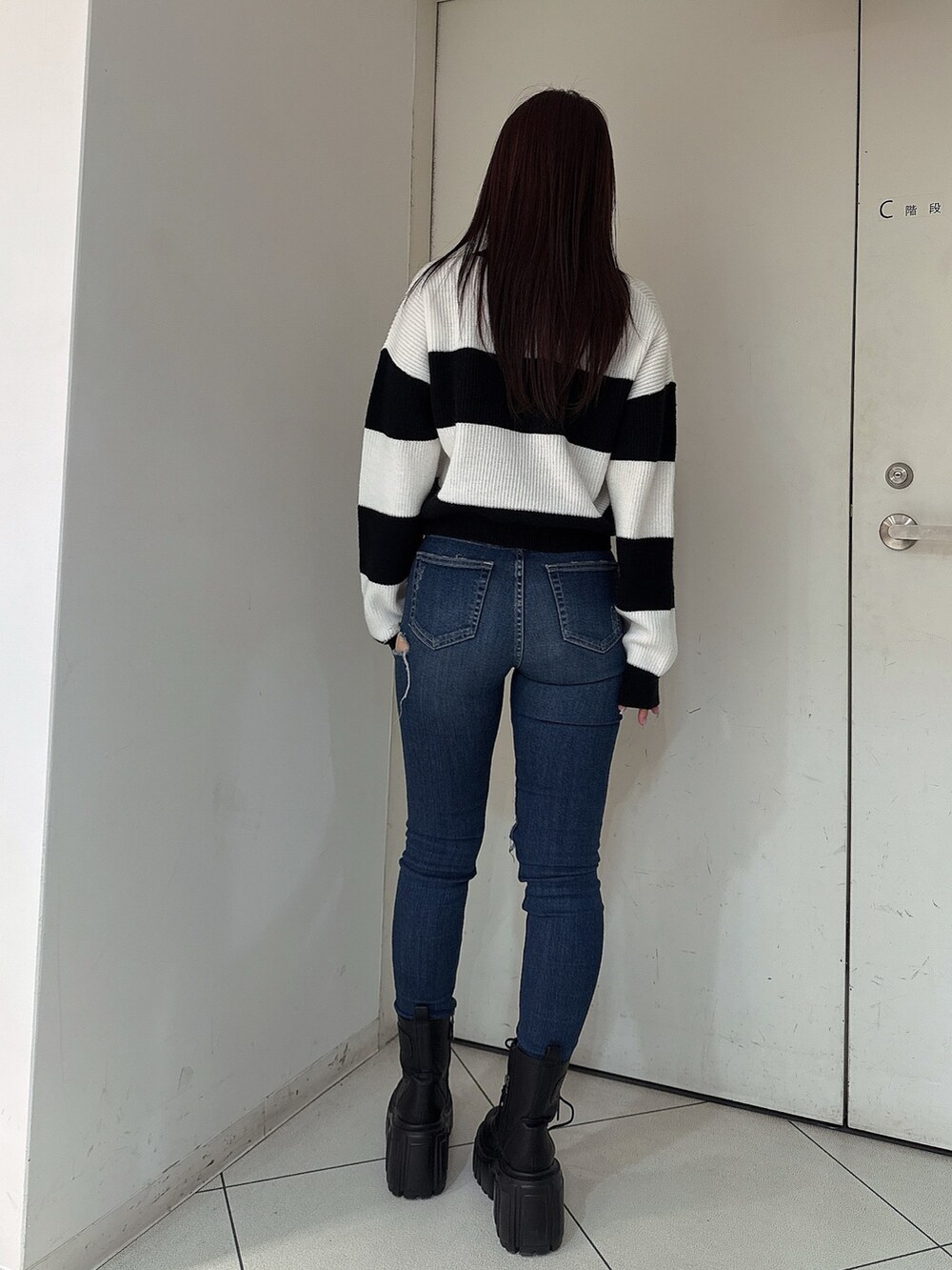 ブルー系のデニムパンツ、ブラック系のブーツ、ブラック系のニット/セーターを着用したレディースの秋コーディネートの3枚目の写真