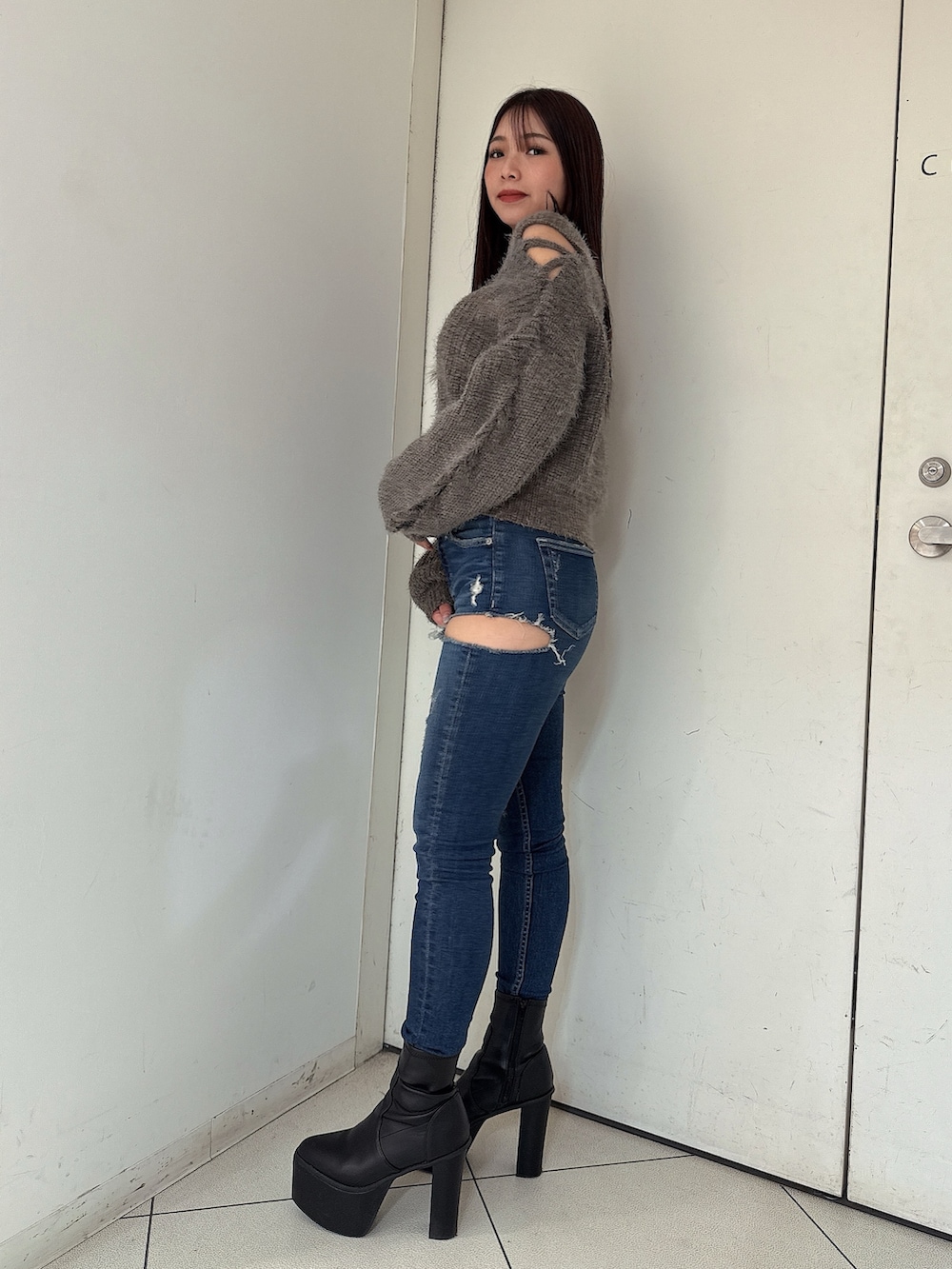 ブルー系のデニムパンツ、ブラック系のブーツ、グレー系のニット/セーターを着用したレディースの秋コーディネートの2枚目の写真