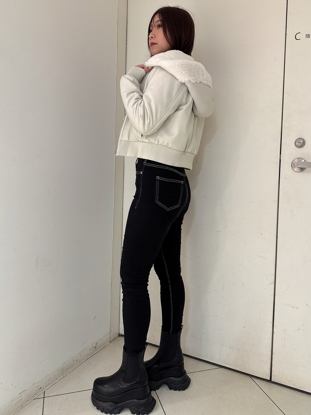 ブラック系のデニムパンツ、ブラック系のブーツ、ホワイト系のその他アウターを着用したレディースの冬コーディネートの2枚目の写真