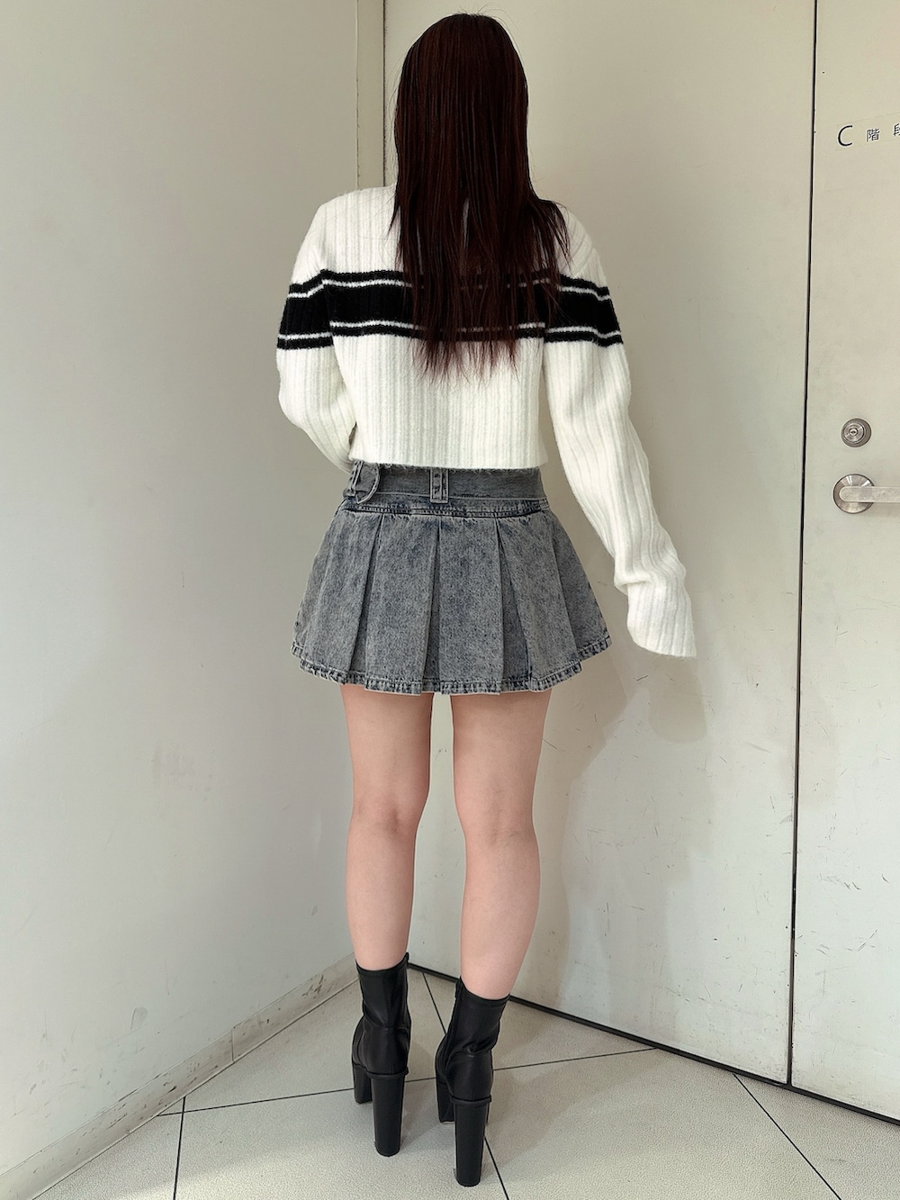 ブルー系のデニムスカート、ブラック系のブーツ、ホワイト系のニット/セーターを着用したレディースの冬コーディネートの3枚目の写真