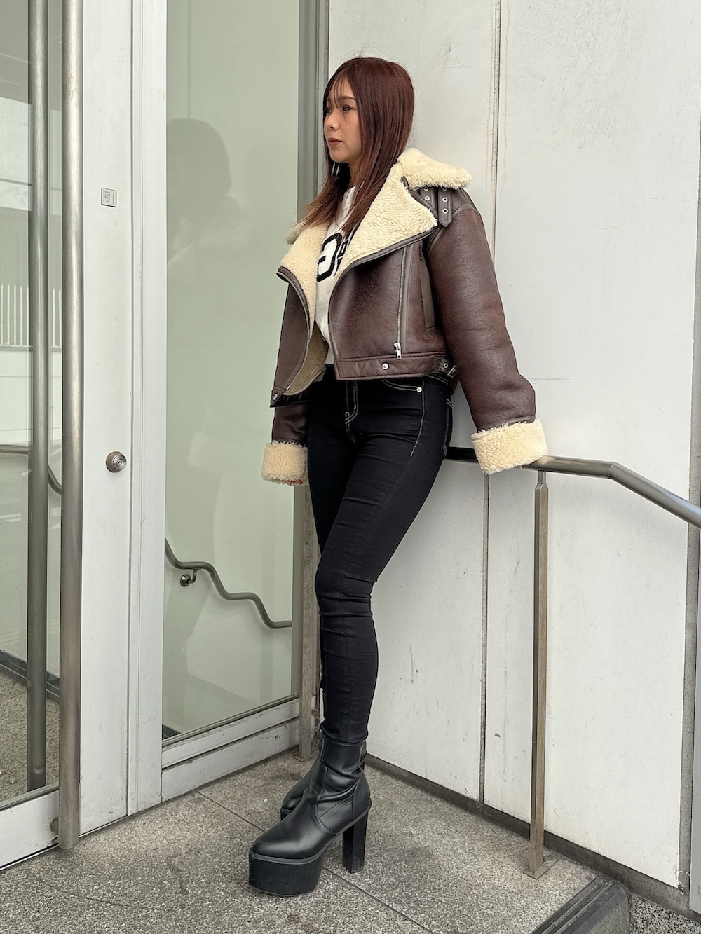 ブラック系のデニムパンツ、ブラック系のブーツ、ホワイト系のニット/セーターを着用したレディースの秋コーディネートの2枚目の写真