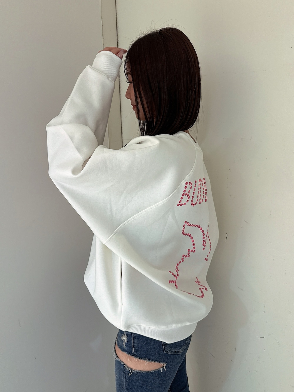 ブルー系のデニムパンツ、ブラック系のブーツ、ホワイト系のスウェットを着用したレディースの冬コーディネートの5枚目の写真