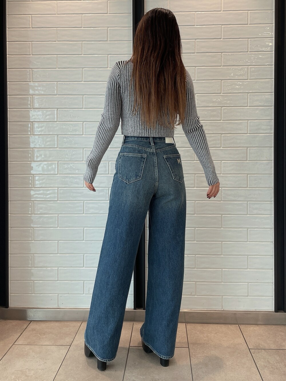 ブラック系のデニムパンツ、ブラック系のブーツ、その他のニット/セーターを着用したレディースの秋コーディネートの3枚目の写真
