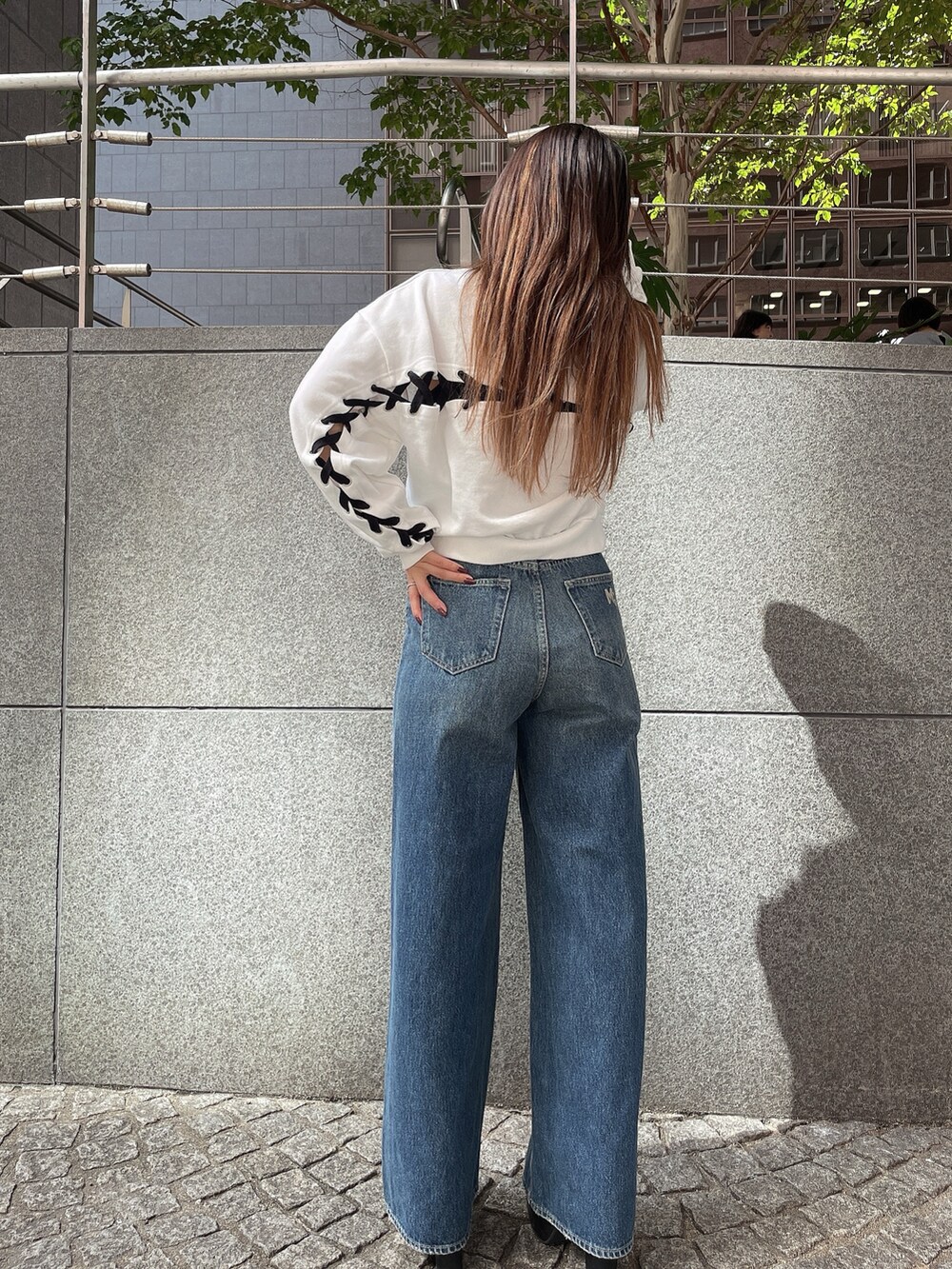 ブラック系のブーツ、ブラック系のデニムパンツ、ホワイト系のスウェットを着用したレディースの秋コーディネートの3枚目の写真