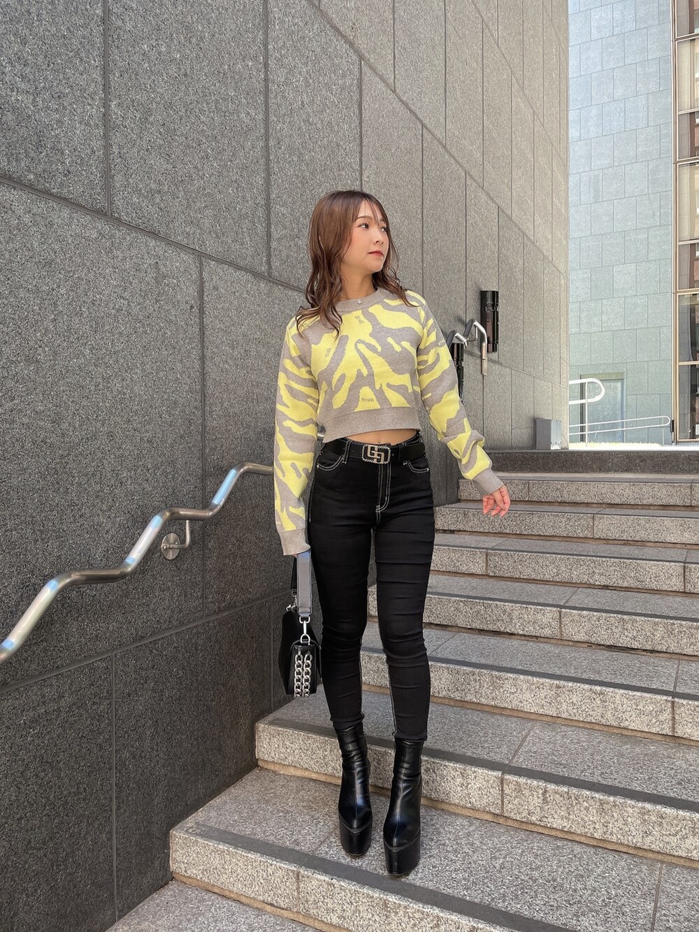 グレー系のニット/セーター、ブラック系のダウンジャケット/コート、ブラック系のデニムパンツを着用したレディースの秋コーディネートの5枚目の写真