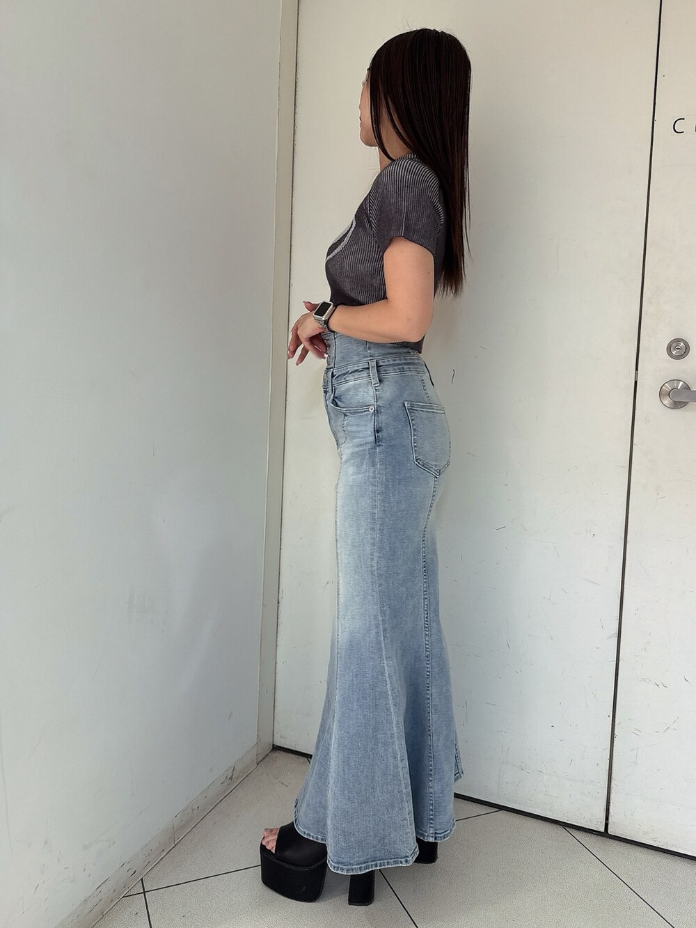 ホワイト系のニット/セーター、ブルー系のデニムスカート、ホワイト系のサンダルを着用したレディースの夏コーディネートの2枚目の写真