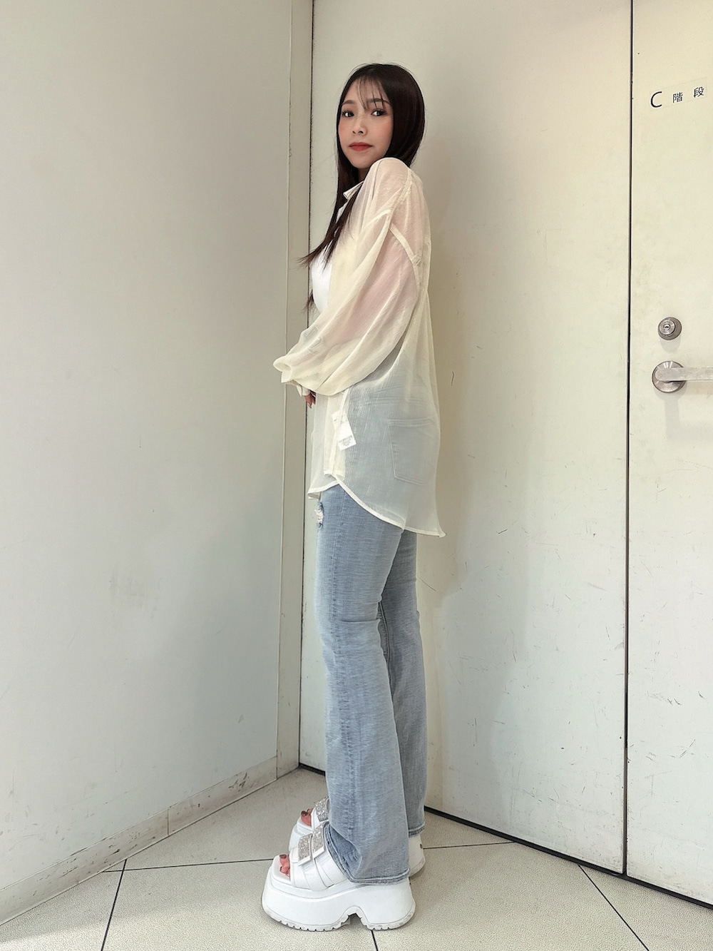 ブルー系のデニムパンツ、ホワイト系のチューブトップ、ホワイト系のシャツ/ブラウスを着用したレディースの春コーディネートの2枚目の写真