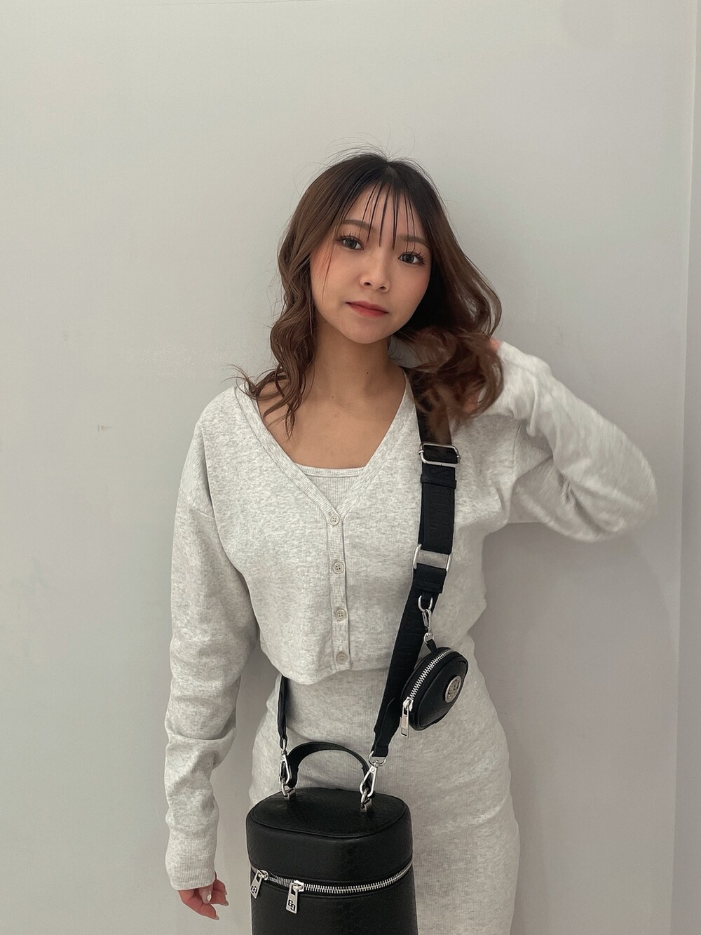 グレー系のワンピース、ブラック系のハンドバッグ、ホワイト系のスニーカーを着用したレディースの春コーディネートの4枚目の写真